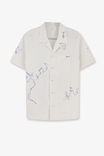 A cream-colored short-sleeved button-up shirt with fine vertical stripes and delicate purple line drawings of musical notes, faces, and leaves.
