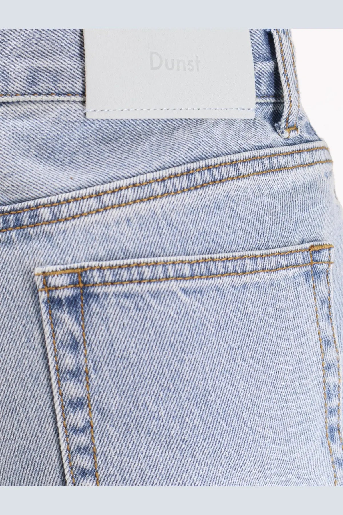 Dunst women’s relaxed flared light-wash denim jeans with white brand label at the waistband showing back side