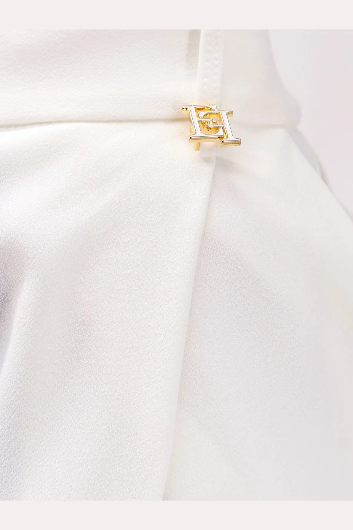 Gold-tone metallic logo clasp with interlocking h design on white fabric of elisabetta franchi women’s essentials stretch trousers