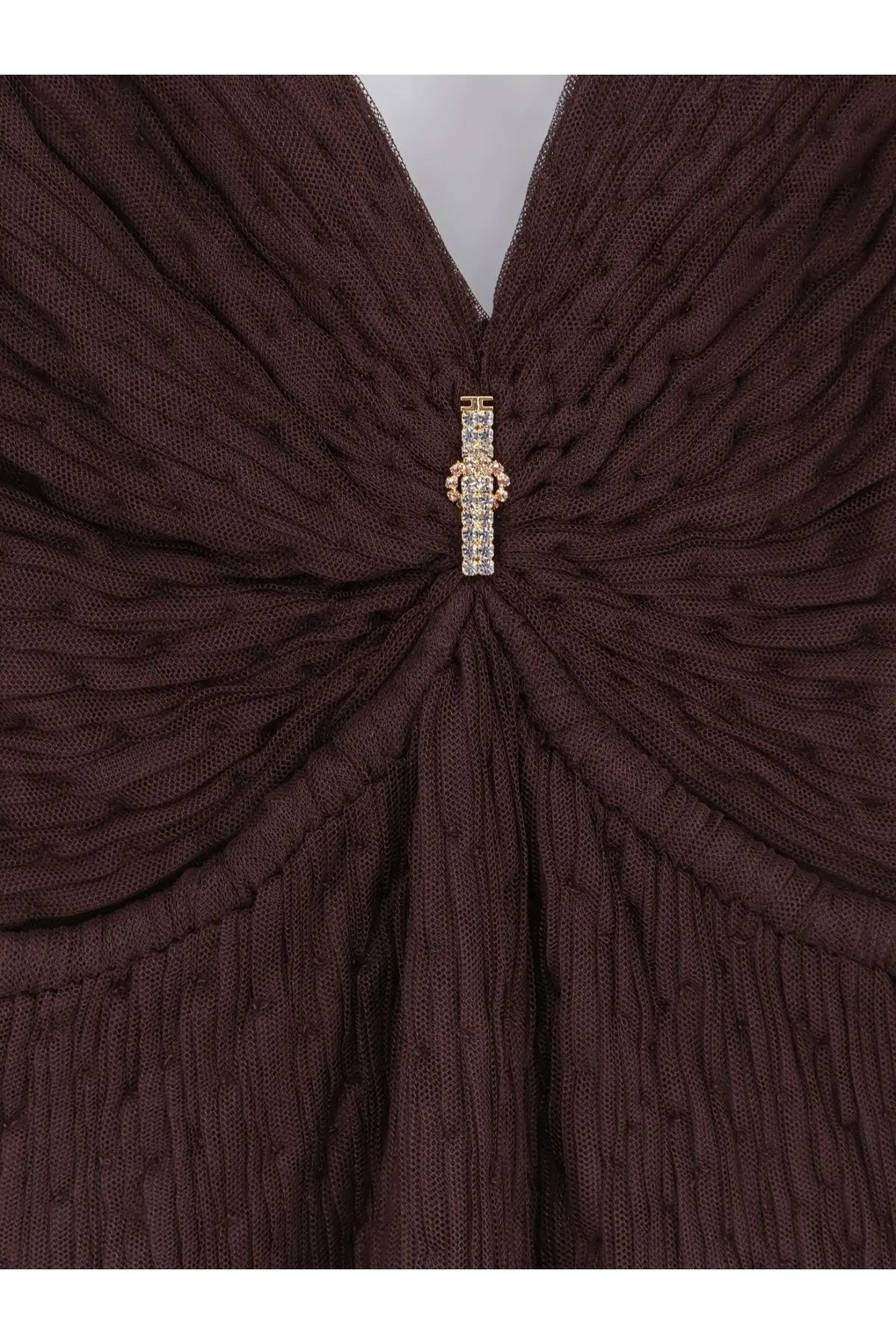 A sparkling gold and crystal brooch adorns the center of a dark brown knitted garment on Elisabetta Franchi dress