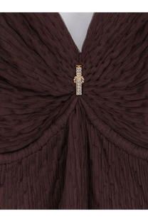 A sparkling gold and crystal brooch adorns the center of a dark brown knitted garment on Elisabetta Franchi dress