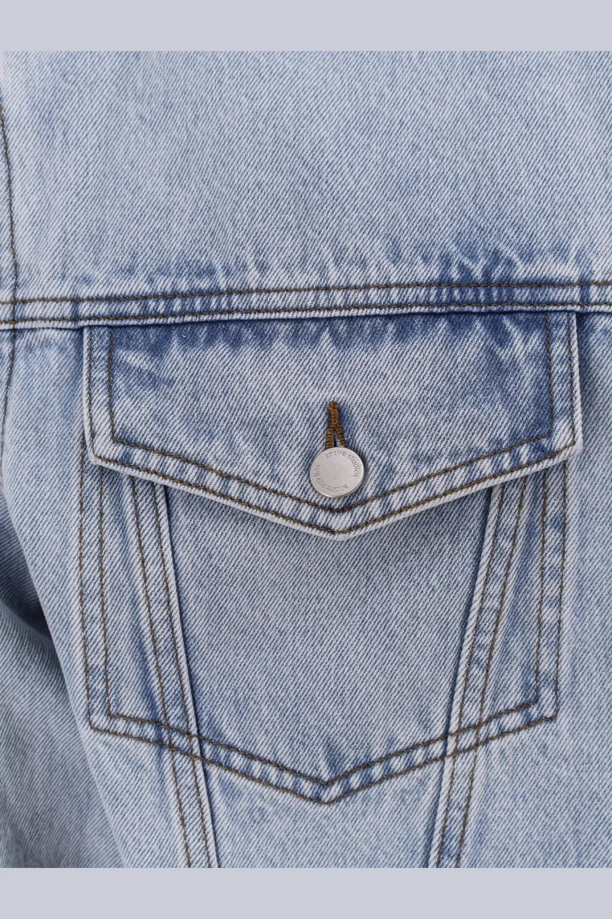 Entire Studios men’s denim jacket blue featuring a light-wash denim pocket with silver button closure detail