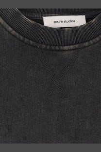 Black ribbed crewneck sweatshirt with subtle faded texture and Entire Studios brand label in cotton blend