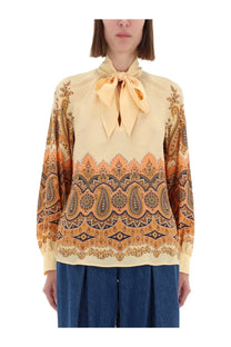 Etro women’s cream-colored blouse with intricate orange and brown paisley pattern and matching fabric bow at neckline