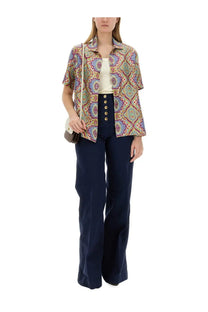 A woman wearing etro women’s multicolor printed silk shirt with short sleeves and intricate purple blue and gold paisley pattern