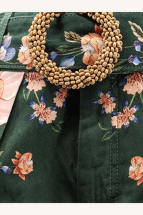 A circular beige beaded belt buckle on dark green floral fabric of Farm Rio womens berry garden cotton shorts black