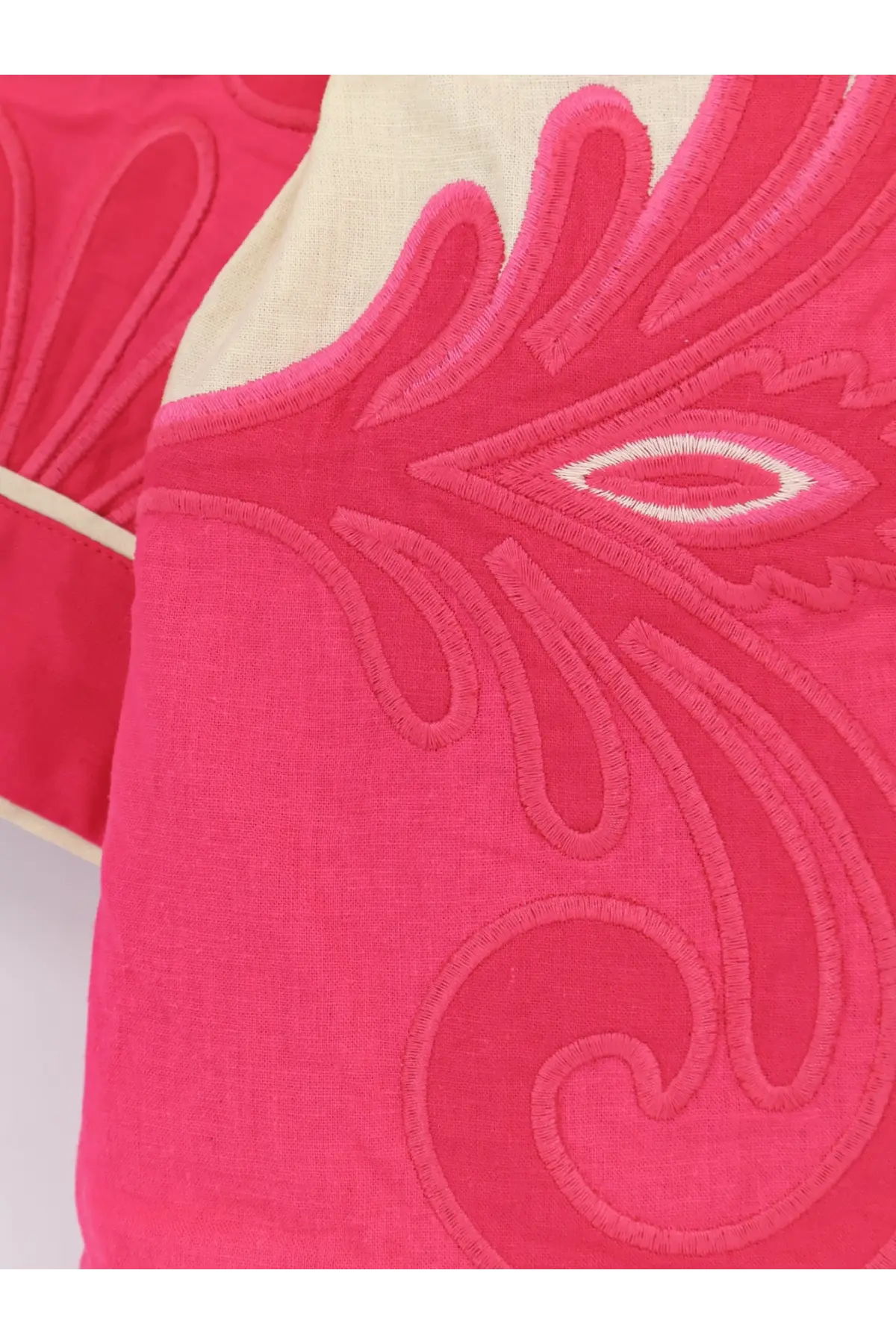 A vibrant pink embroidered cushion with cream border shown with farm rio women’s blue linen and viscose kimono