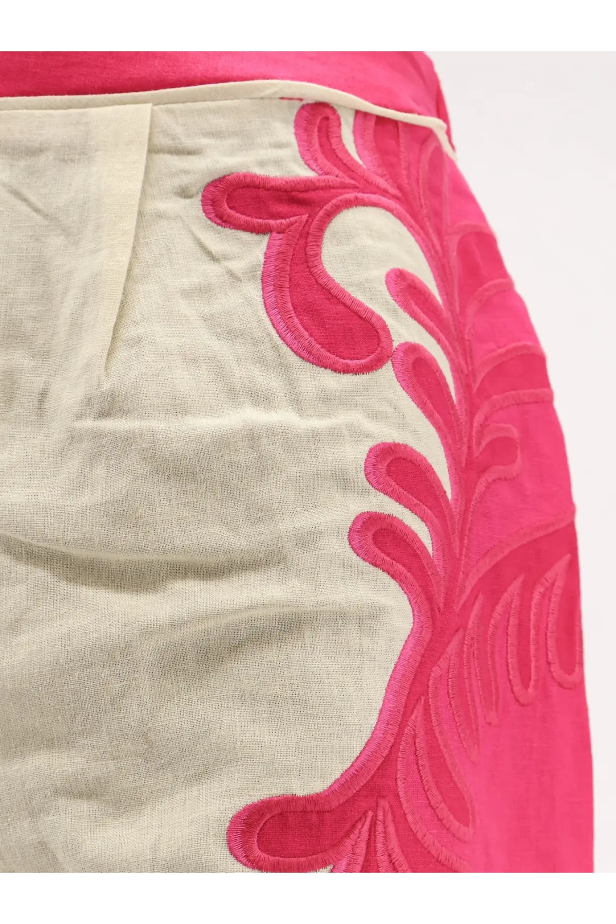 A vibrant pink embroidered leaf pattern adorns the side of a light beige linen skirt in farm rio trousers collection