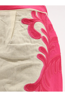 A vibrant pink embroidered leaf pattern adorns the side of a light beige linen skirt in farm rio trousers collection