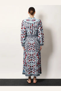 A woman wearing a FARM Rio women’s Marcelle maxi dress blue with a red and navy floral pattern on light blue fabric