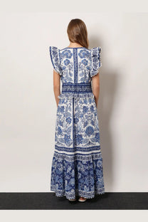 A woman wears a white and navy blue FARM Rio shell garden cotton long dress with floral embroidery and ruffled sleeves