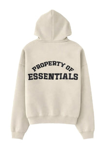 Back view of fear of god essentials men’s beige zip hoodie with property of essentials printed in bold black letters