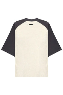 Cream baseball-style fear of god essentials men’s shirt with dark gray raglan sleeves and black neckline tag