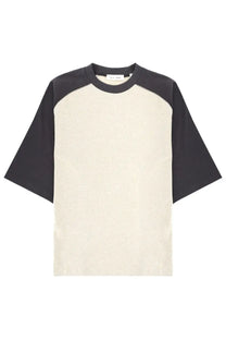 Cream-colored and black raglan-sleeved fear of god essentials men’s shirt with relaxed fit and signature baseball design