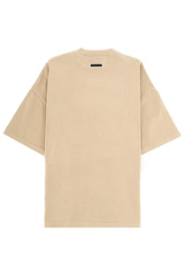Beige Fear Of God Essentials oversized men’s training t-shirt with short sleeves and black tag at the neckline