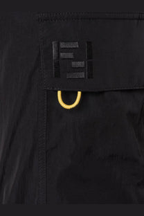 Close up of black fendi logo patch with yellow metal ring on fendi men’s cargo nylon trousers in black