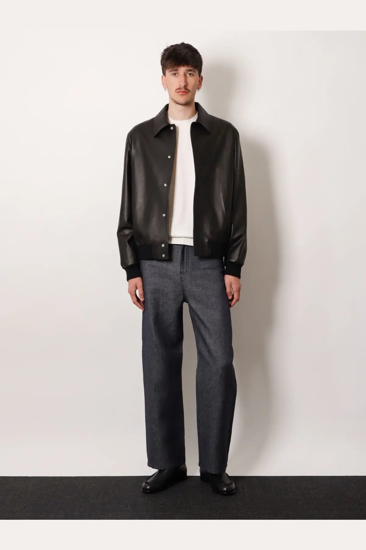 Black leather bomber jacket showcasing premium leather texture paired with Fendi men’s cotton and cashmere white sweater
