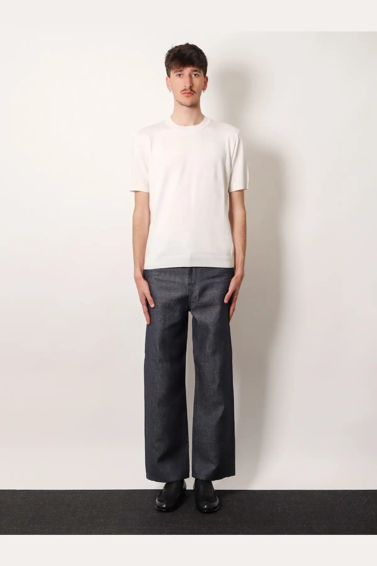 Fendi men’s white cotton and cashmere sweater paired with a minimalist white short-sleeved cotton t-shirt and dark gray trousers