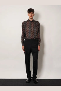 A man wearing a dark long-sleeved geometric patterned shirt paired with black Fendi men’s virgin wool trousers
