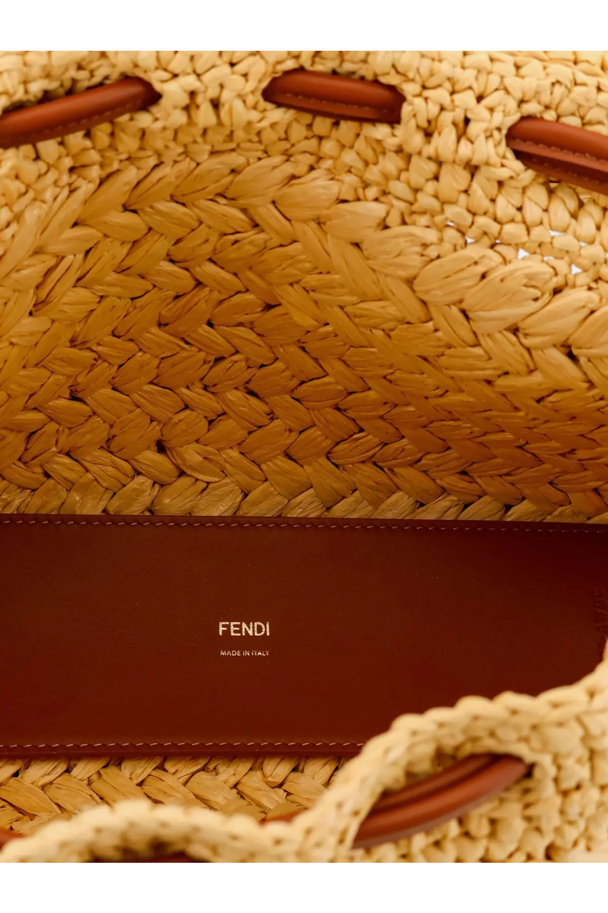 A tan woven raffia Fendi mamma baguette medium crossbody bag with brown leather handles and logo strap white background