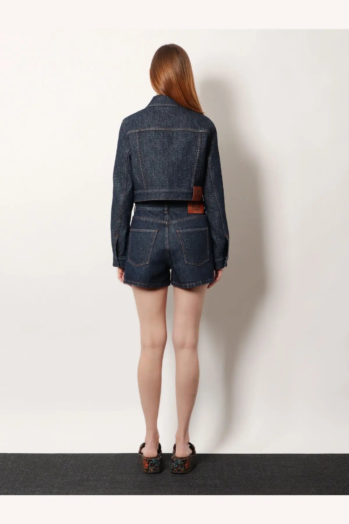 Back view of fendi women’s padded dark blue denim cropped jacket with brown leather patch on waistband