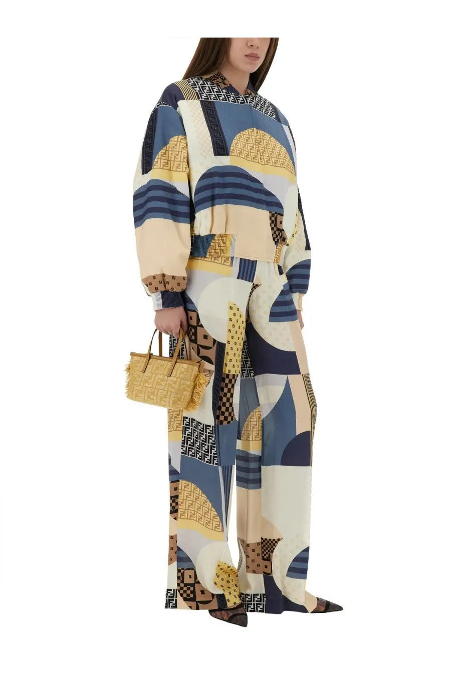 A woman wears a fendi patchwork silk jumpsuit with bold geometric navy beige yellow patterns and ff logos