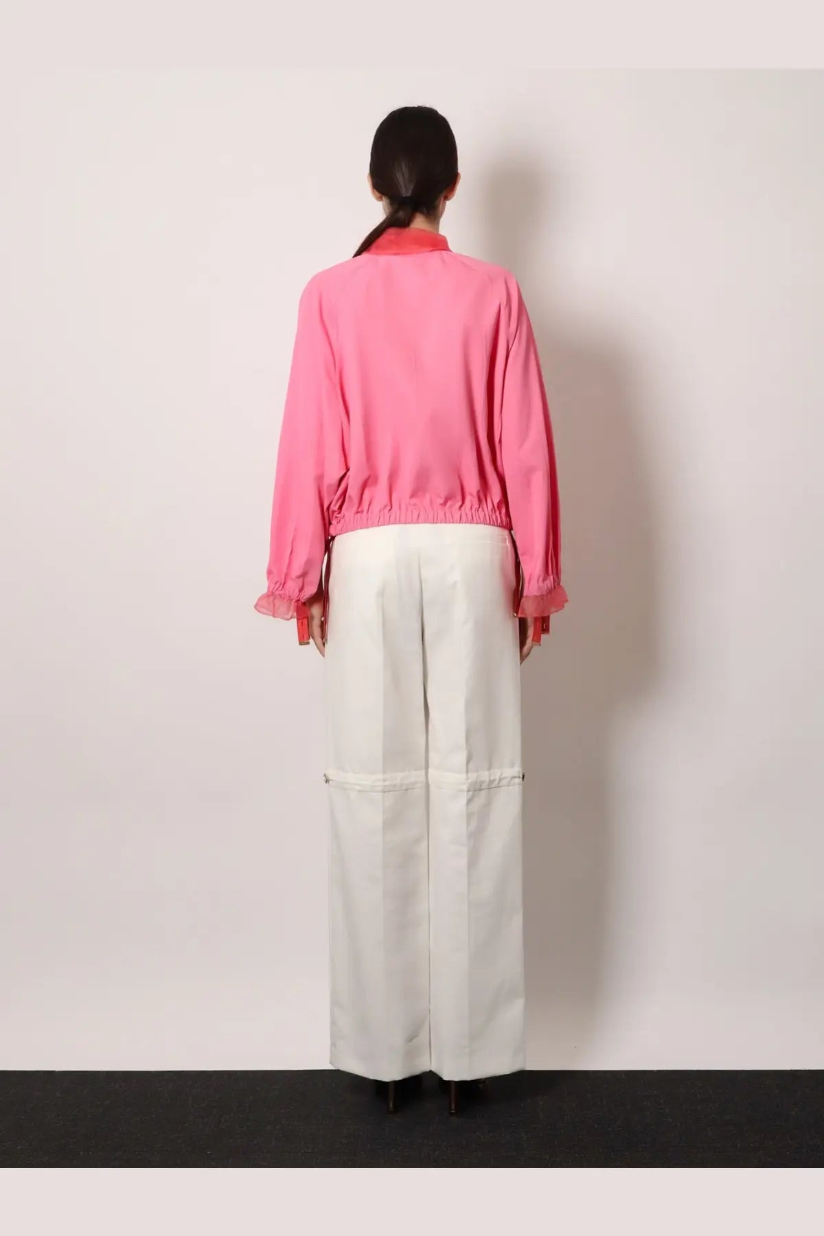 A vibrant pink cropped jacket with ruffled cuffs and collar paired with Fendi women’s white technical canvas trousers