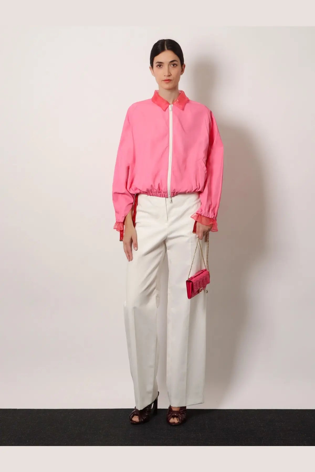 Pink satin clutch with chain strap paired with Fendi women’s azalea technical viscose jacket front view