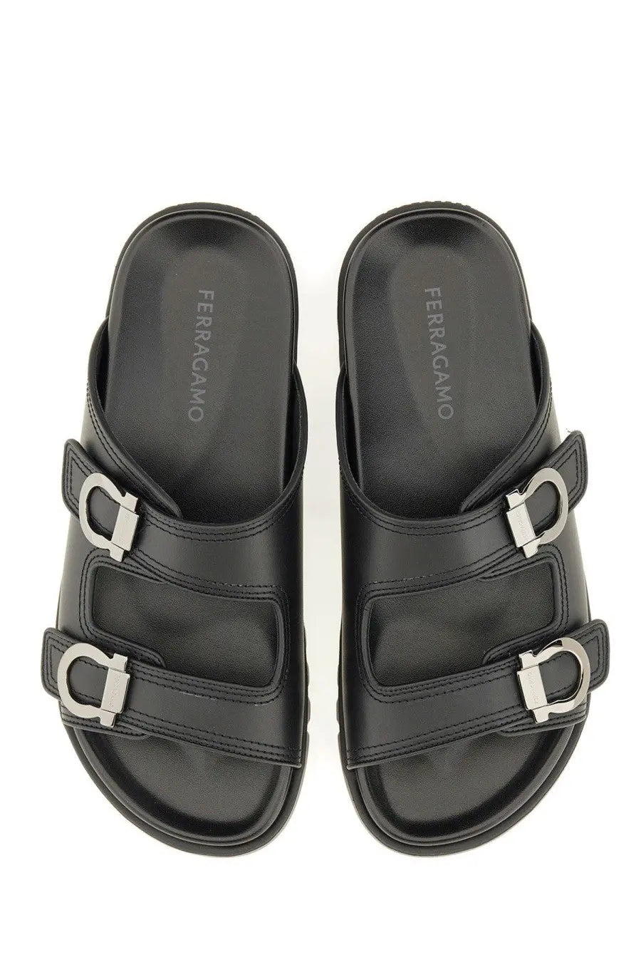 Ferragamo men’s black leather slide sandals with silver metal buckles and cushioned soles showing the insole logo