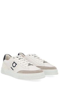 White low-top ferragamo men’s gancini sneaker with navy branding and gray suede toe cap and heel accents