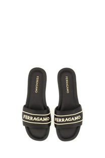 Black Ferragamo women’s slide sandal with a contrasting white logo band across the leather foot strap