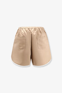 Beige satin boxer shorts with elastic waistband and white trim along the hem from the frankie shop women’s adia collection