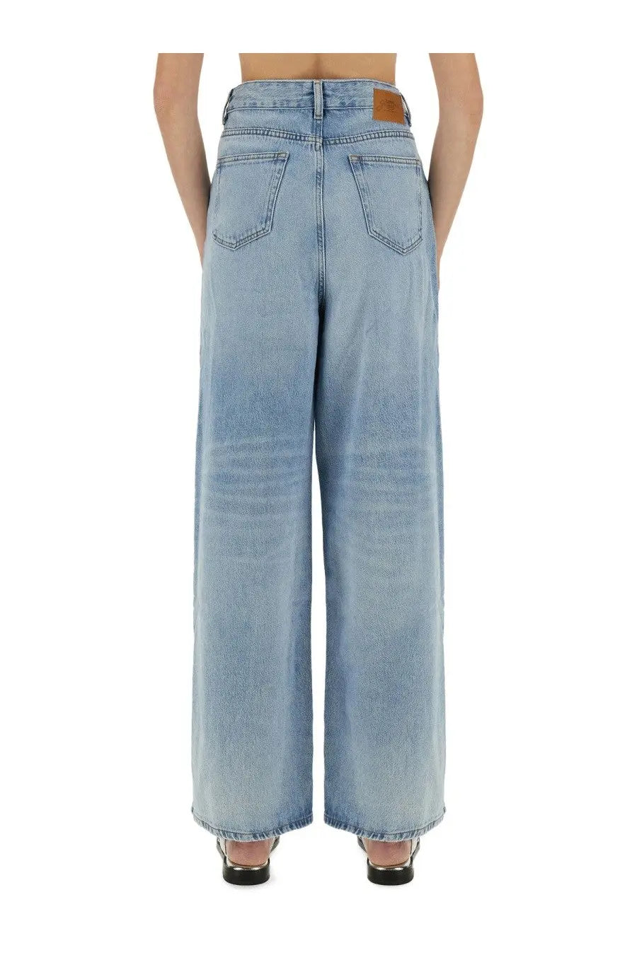 Back view of ganni women’s baggy blue jeans in light-wash denim with classic pockets and brown leather waistband patch