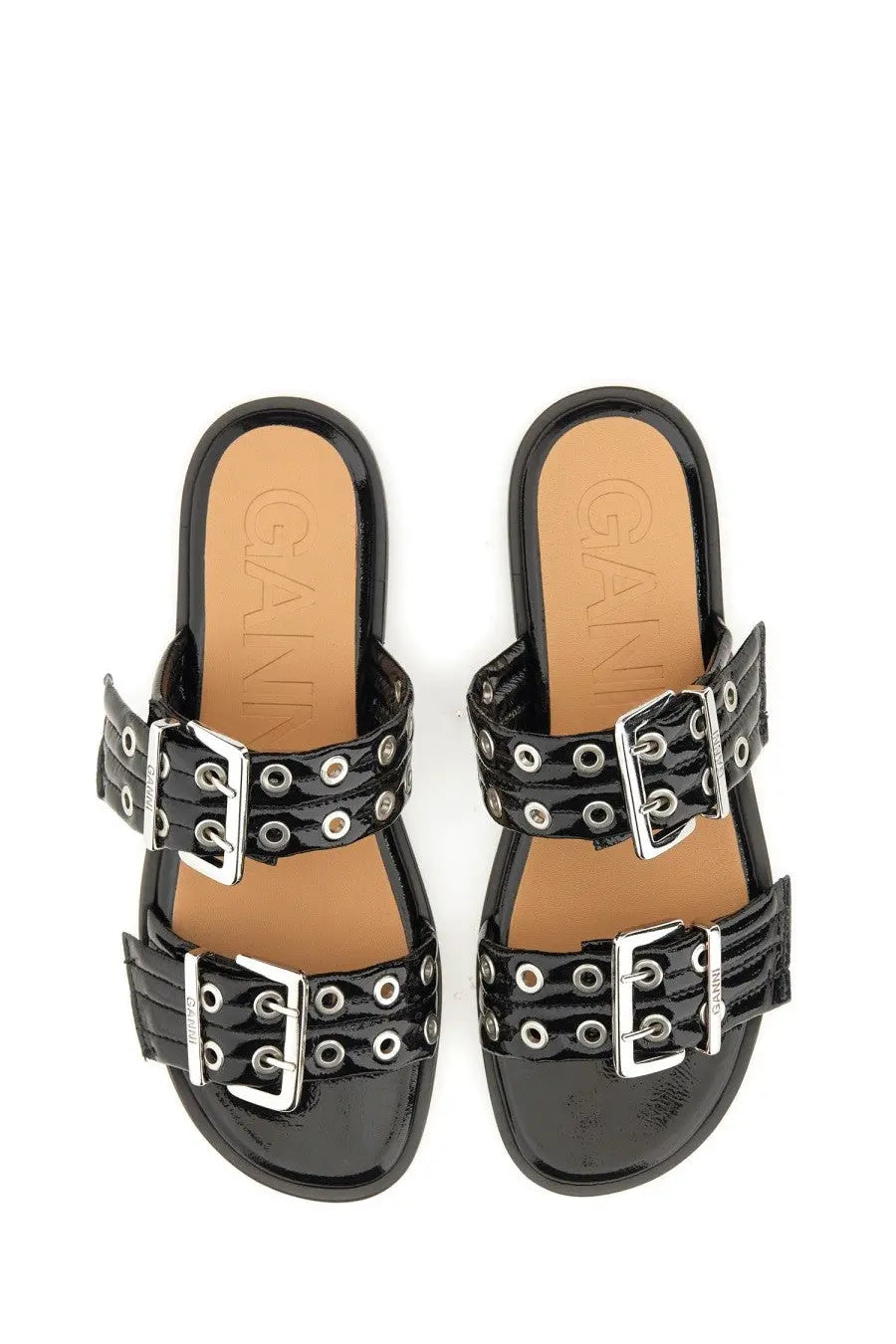 Black patent leather slide sandals by ganni with silver double buckle straps and circular eyelets