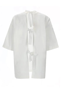 The garment women’s blusa cyprus white loose fitting blouse with short sleeves and back tie detail shown from the back