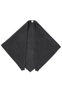 The garment women’s clooney scarf grey shown with a black woolen poncho featuring a subtle textured weave and minimalist branding