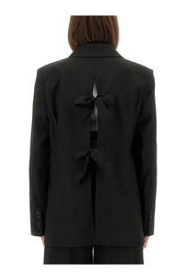 The garment women’s pluto blazer black showing the back with a central bow detail on a tailored black blazer
