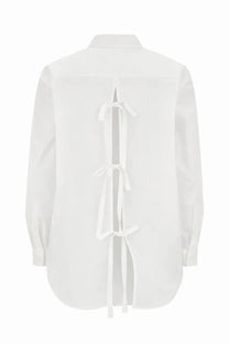 The back side of a minimalist white cotton blouse with a distinctive back tie detail from the garment womens shirt cyprus white