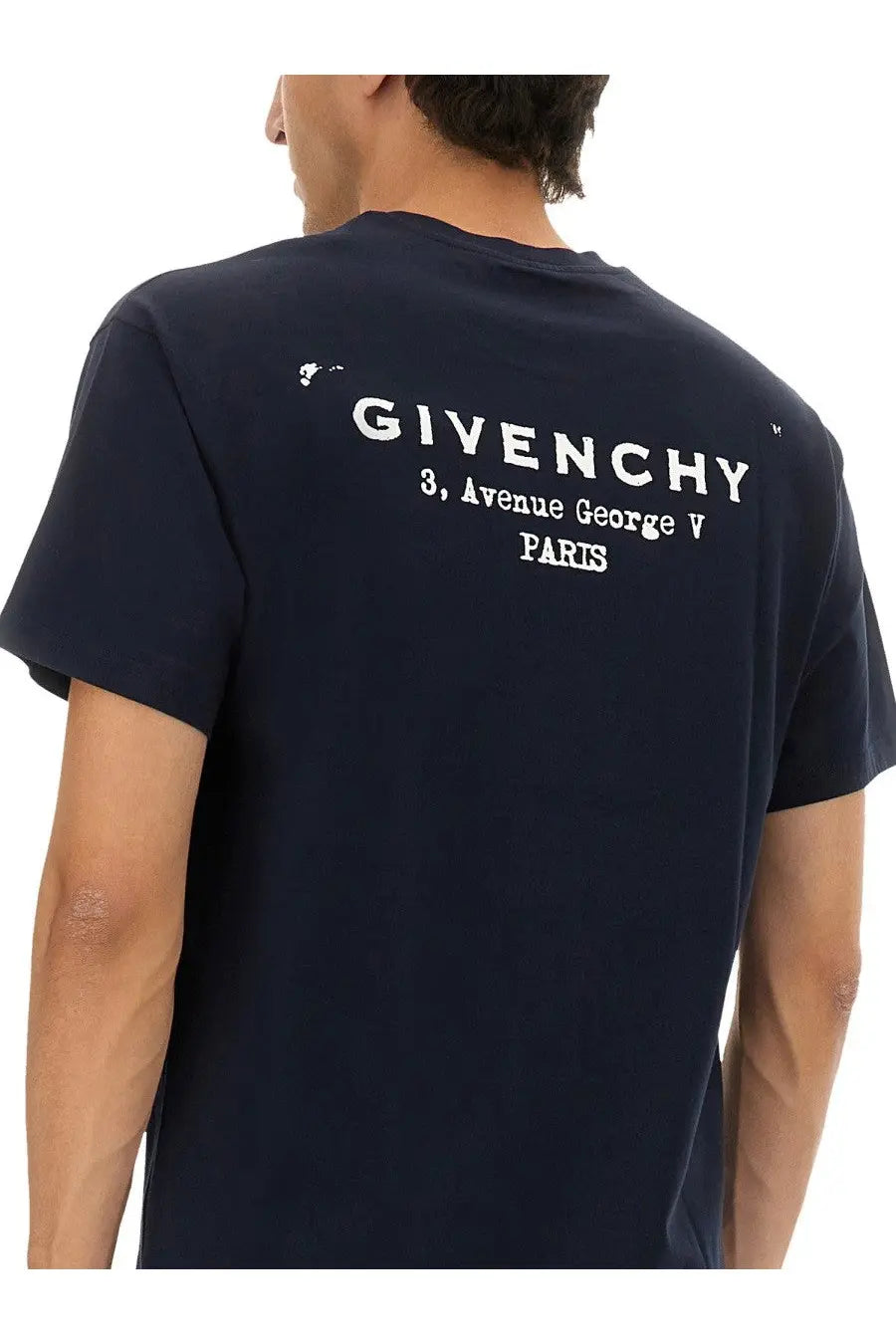 Back view of a navy blue Givenchy men’s regular fit shirt with white printed logo and address text on cotton fabric