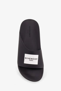Givenchy men’s rubber slide sandal in black with minimalist design and white rectangular logo patch on the footbed