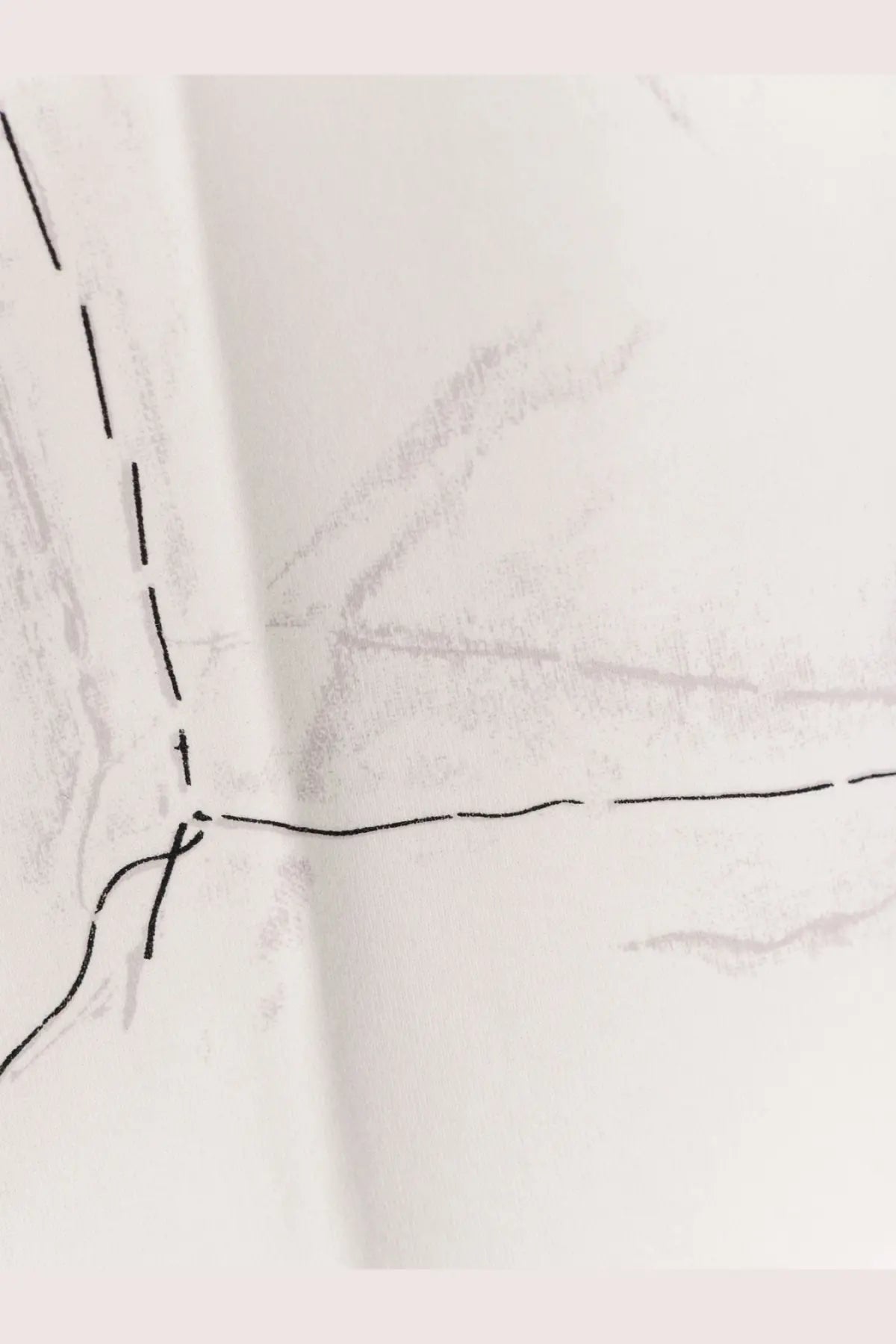 A close-up of a white cotton Givenchy women’s shirt showing faint pencil sketch markings and black stitching lines