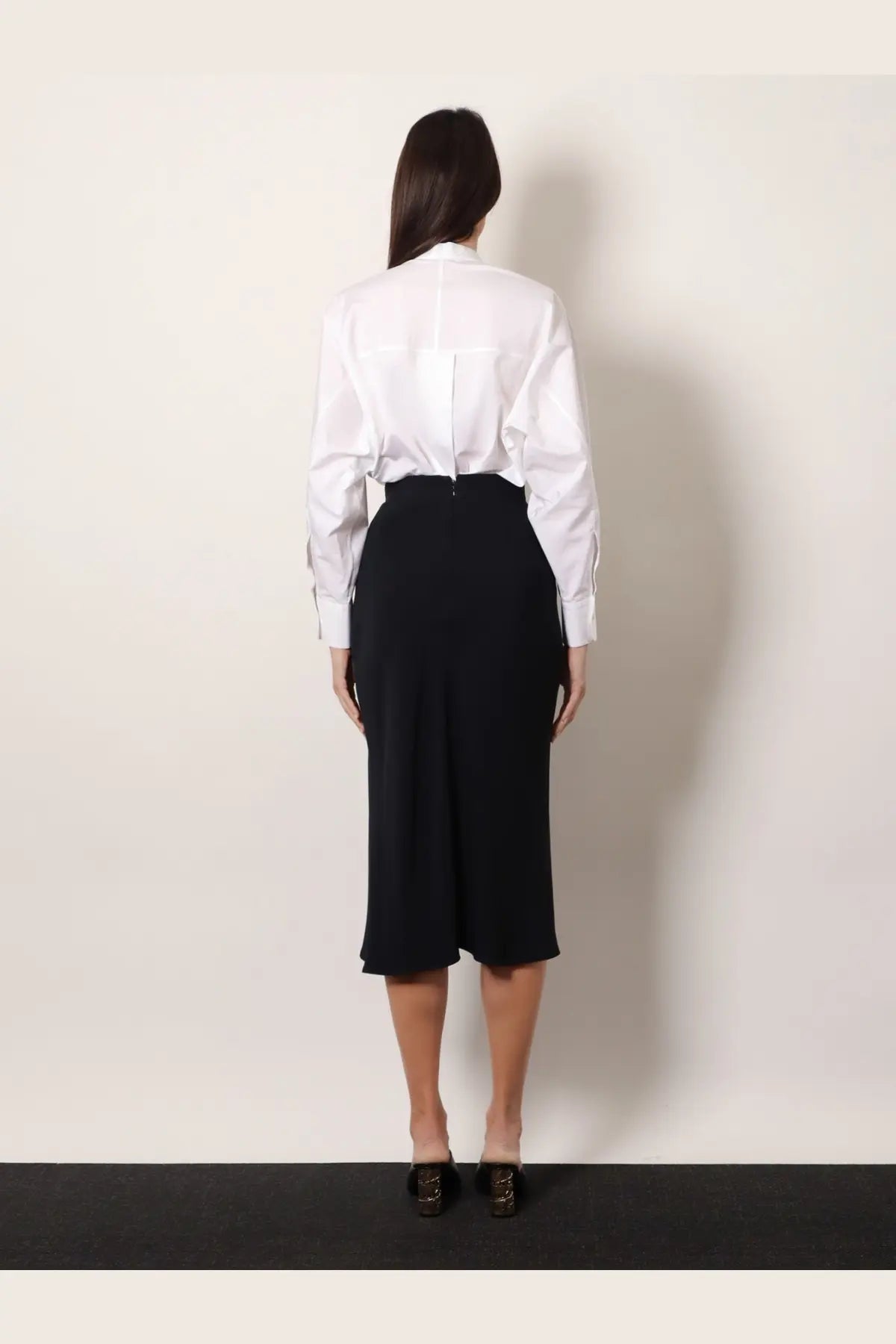 A woman wearing a crisp white shirt paired with Givenchy women’s draped black midi skirt in front view