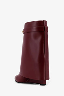 A sleek burgundy Givenchy women’s shark leather boot with a wedge heel and gold-tone buckle detail