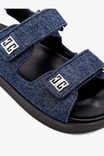 Givenchy women’s flat denim sandals in blue featuring silver metallic logo accents on the straps