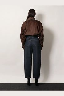 Brown satin bomber jacket with white trim at collar and cuffs paired with Givenchy women’s twisted dark blue denim jeans