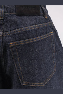 Givenchy women’s twisted dark blue denim jeans with tan stitching and black brand label at the waistband