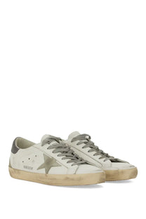 Golden Goose Mens Super Star white leather sneakers with distressed finish, gray laces, metallic star