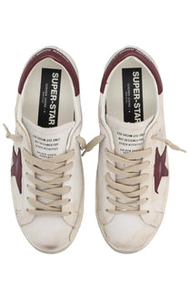 Golden goose men’s superstar sneaker white with white leather low-top design and maroon star accents and heel tabs