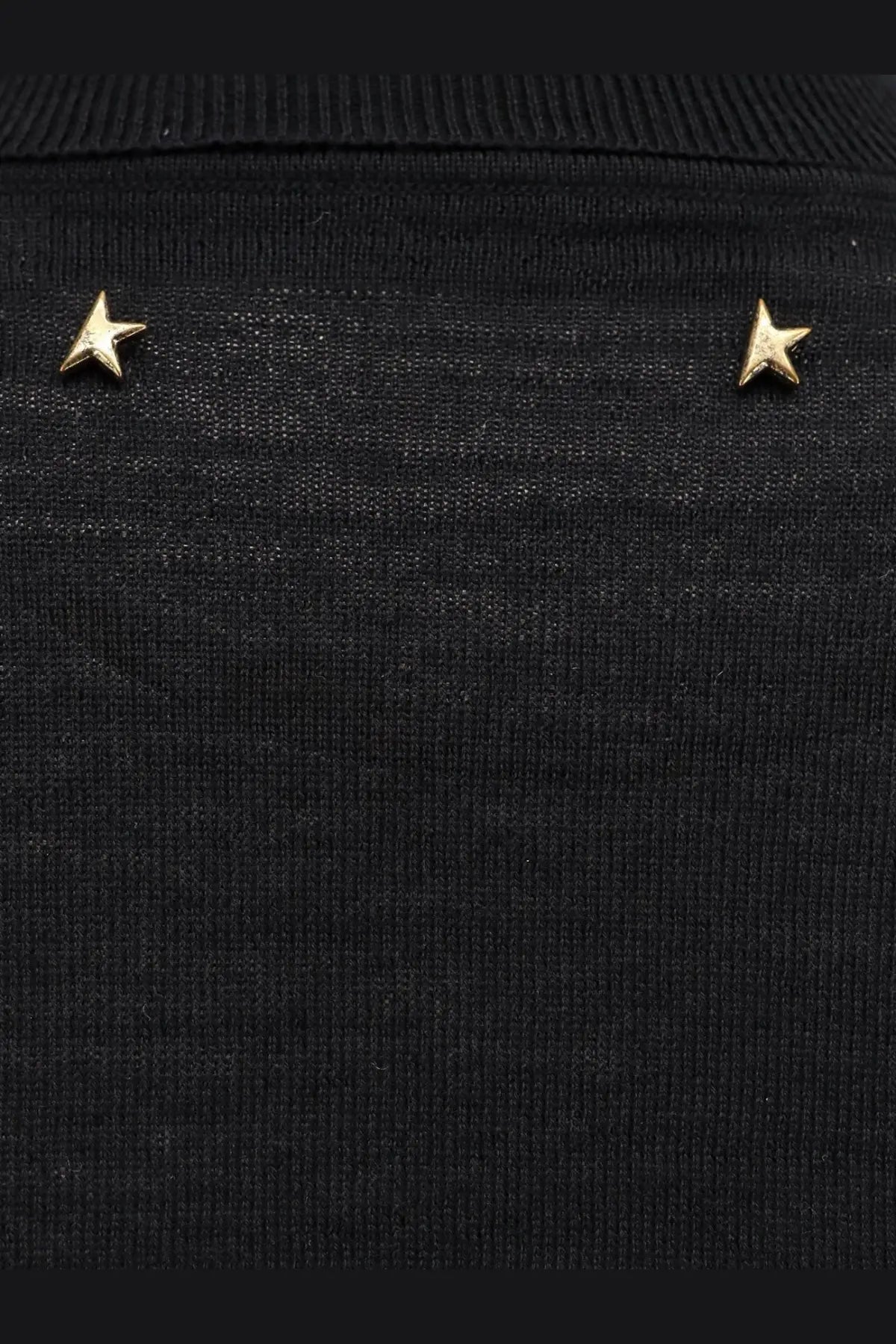 Gold star-shaped stud earrings displayed on a black virgin wool knit sweater from golden goose women’s dilara collection