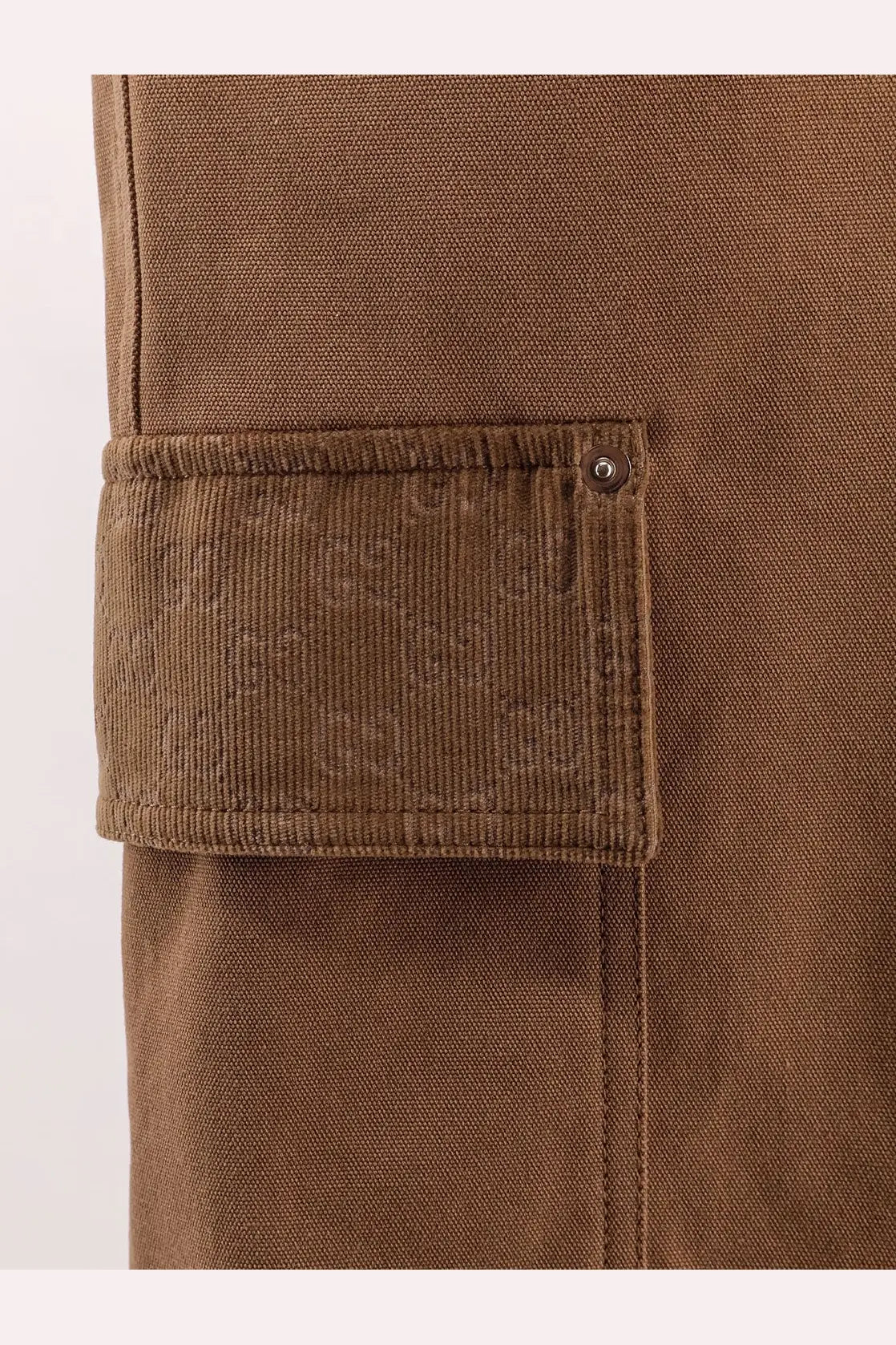 Beige gucci men’s canvas shorts featuring a brown corduroy cargo pocket with textured weave and dark metal snap closure